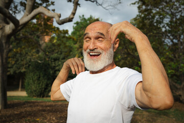 Happy senior man exercising in park on sunny day