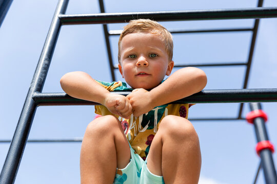 Boy sitting on monkey bar at playground
