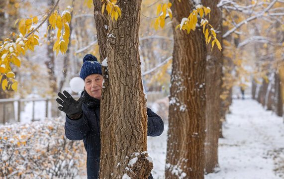 Happy senior man throwing snowball in winter park