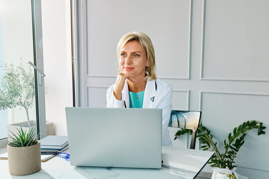 Contemplative doctor sitting near laptop in private medical office