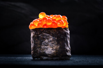 Ikura sushi maki roll on a black slate background © laplateresca