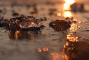 Zamarznięte jezioro, kra na wodzie w ciepłych promieniach słońca.