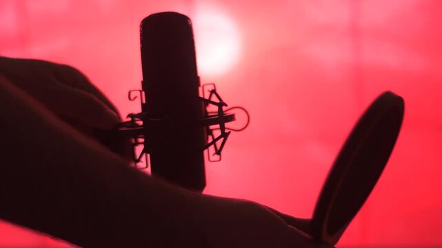 An audio technician turns off a professional microphone. Disconnecting the cable from the socket.