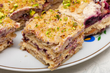 Slice of dessert with nuts on top. The dessert is cut into a square and is sitting on a white plate