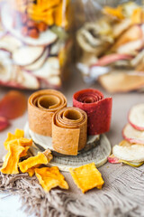 Freshly rolled, homemade fruit leather and dried fruit slices made from organic ingredients are displayed on a rustic table