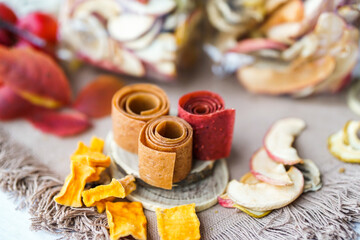 Freshly rolled, homemade fruit leather and dried fruit slices made from organic ingredients are displayed on a rustic table