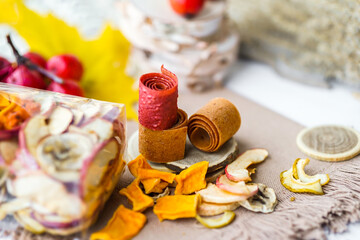 Freshly rolled, homemade fruit leather and dried fruit slices made from organic ingredients are displayed on a rustic table