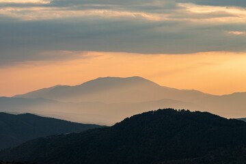 Obraz premium Mountain landscape at sunset with orange sky.