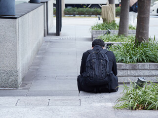 冬の朝の都市のビジネス街で休憩する一人の若い男性サラリーマンの姿