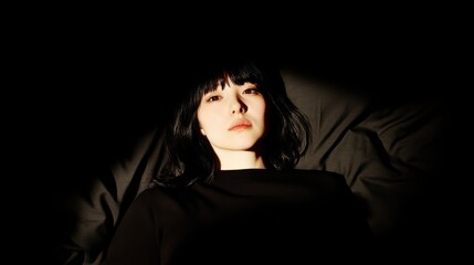 Naklejka premium Mysterious portrait of a young woman in shadows with intense gaze