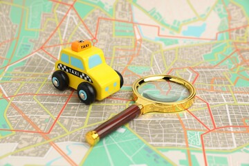 Yellow taxi car and magnifying glass on city map. Road trip