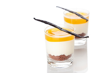 New York Cheesecake dessert with mango topping in glasses, garnished with vanilla pods, white background