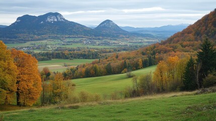 Obraz premium Vibrant autumn alpine landscape showcasing rolling hills mountains and colorful foliage under a cloudy sky in a serene natural setting