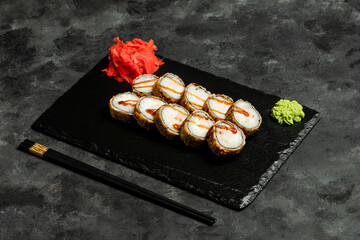 Sushi rolls, red pickled ginger and wasabi on black tray