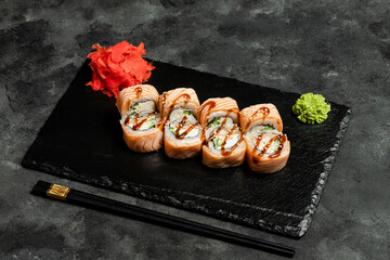 Sushi rolls, red pickled ginger and wasabi on black tray