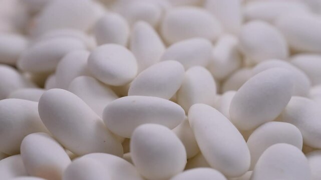 Close up view. Heap of white chocolate covered almond nuts. Glazed white dragees. Slider shot. Depth of field, selective focus. Candies, sweet treats, snacks, confectionery concepts. 4k