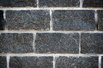 Wall of stones. Brick wall. Gray background with black geometric patterns, of rectangular stones, bricks. Part of a stone wall pattern for background, texture or text. rough grainy stone wall