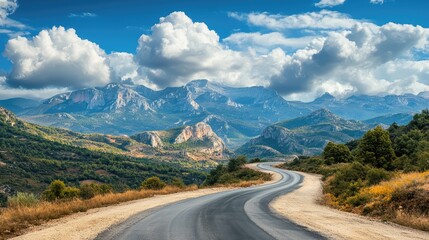 Naklejka premium Winding road through sandy clay soil with majestic mountains and white clouds in a scenic landscape vision