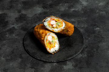 Fried sushi burrito sliced on black plate