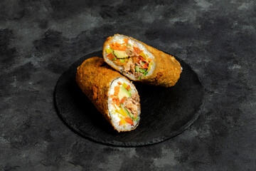 Fried sushi burrito sliced on black plate