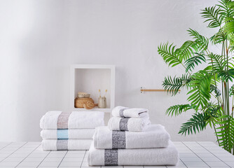 White and grey towels in a row, vase of plant background with bath room objects cabinet.