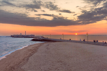 A stunning sunset over La Caleta Beach in Cadiz, Spain. The picture shows the famous pier and San Sebastian Castle in the background © Kavalenkava