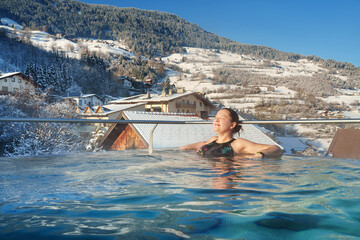 A woman relaxes in swimming pool in winter season. Winter resort for winter holiday - vacation.