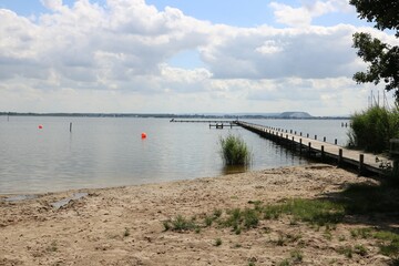 Fototapeta premium Blick vom Strand Weiße Düne in Mardorf auf das Steinhuder Meer mit Kaliberg und Bootsteg