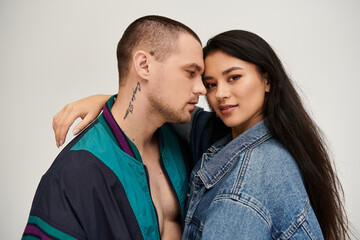 A beautiful young couple shares an intimate moment in stylish attire, celebrating their love.