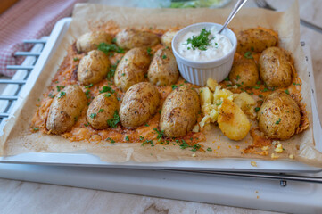 Parmesan baked jacked potatoes on a baking tray with a dip. Delicious party food
