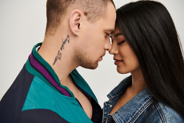 A beautiful young couple shares an intimate moment dressed in fashionable attire, celebrating love.