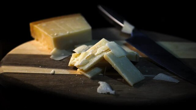 parmesan cheese on a wooden board and pieces of parmesan cheese falling from above in slow motion