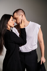 A young couple dressed fashionably embraces, radiating love and connection in a studio.