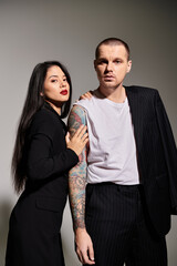 A couple exudes romance in a studio, showcasing stylish attire and deep affection for each other.