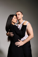 A young couple in fashionable attire shares an intimate moment in a studio setting, exuding love.