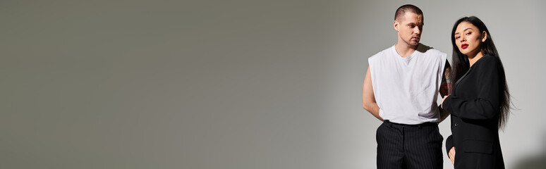 A beautiful young couple poses in fashionable attire, showcasing love and elegance in a studio, banner