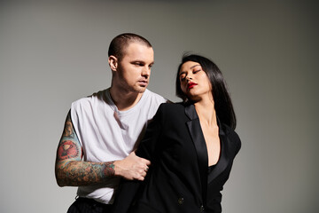 A beautiful couple dressed in stylish attire expresses love in an artistic studio setting.