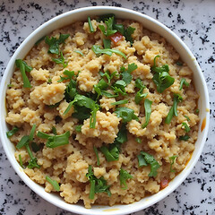 Bowl of fluffy grain dish garnished with fresh herbs