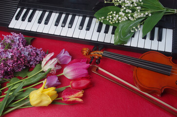 Violin, bow, synthesizer keyboard and a bouquet of flowers on a red background.
