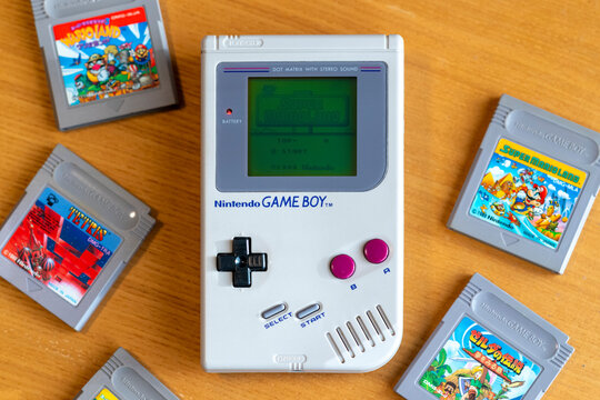 Fukuoka, Japan - december 30, 2024 : 1989 hit game super marioland running on original nintendo game boy on a wooden table with various other hit game cartridges 
