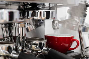 Professional espresso coffee machine while preparing espressos coffee red cup.Close-up of black coffee menu pouring from the coffee machine in cafe.