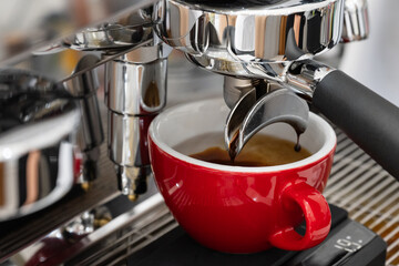 Professional espresso coffee machine while preparing espressos coffee red cup.Close-up of black coffee menu pouring from the coffee machine in cafe.