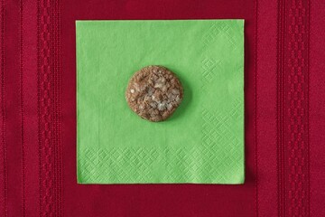 Home made espresso coin cookie on a green napkin and red table cloth. 