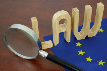 Letters law on European Union flag under magnifying glass. EU laws concept.
