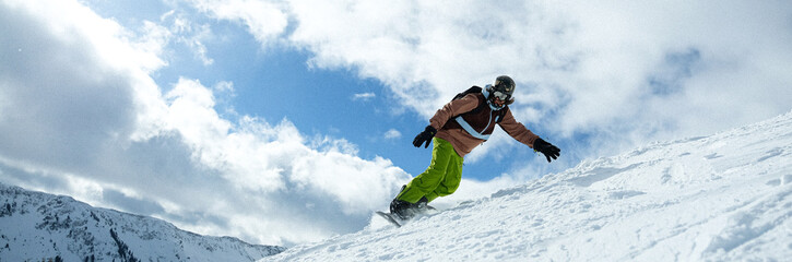 Snowboarder descending a steep mountain slope, surrounded by breathtaking alpine scenery. A...