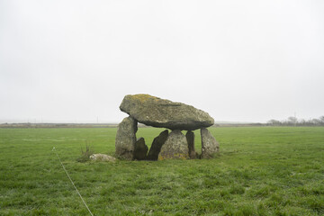 Carreg Samson, a prehistoric dolmen with a large capstone supported by upright stones, surrounded by lush grass and mist, evoking a serene, mystical atmosphere in a tranquil landscape.