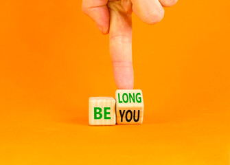 Belonging and belong symbol. Concept words Be you Belong on beautiful wooden block. Beautiful orange background Businessman hand. Business motivational belonging and belong concept. Copy space.