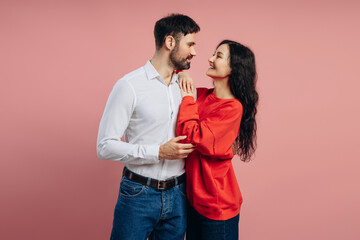 Happy couple embracing and smiling on pink background