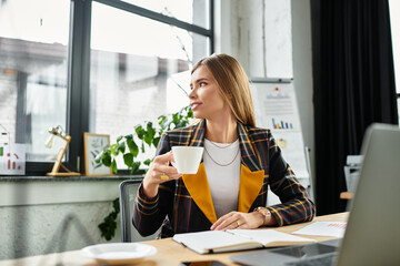 Young professional with a stylish checkered blazer sips coffee in a contemporary workspace.