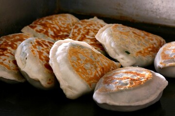 Golden-brown fried dumplings on a griddle.